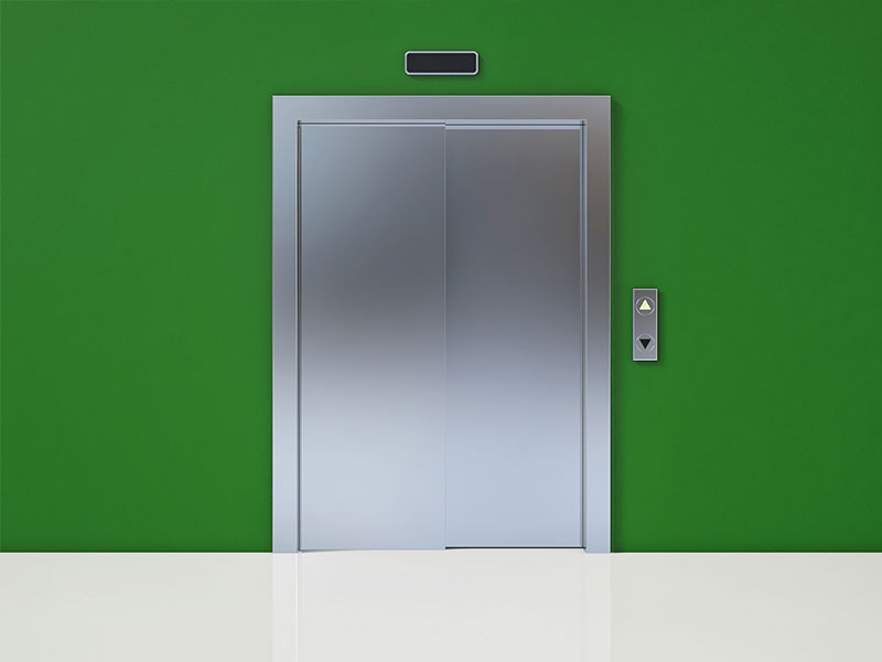 Geschlossene Aufzugstür in einer grüngestrichenen Wand