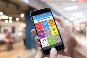 Foto von zwei Händen, die ein Smartphone halten, auf dessen Bildschirm die bunten Kacheln des DAKS Mobile Client zu sehen sind