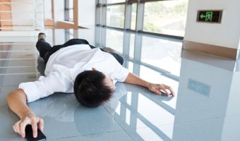 Mann liegt bäuchlings auf dem Boden eines Flurs mit einem Smartphone in der rechten Hand